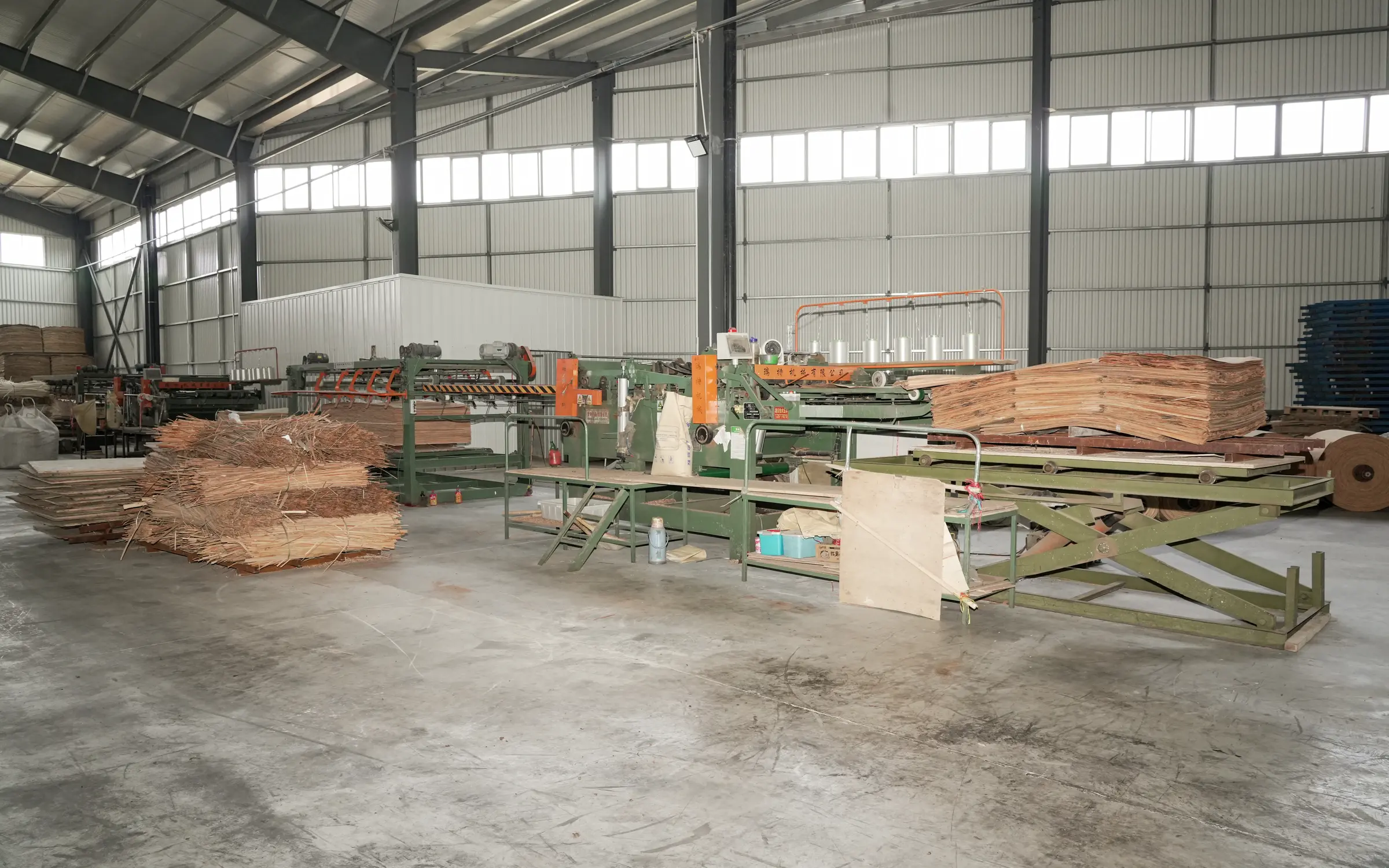 Prepared veneer sheets stacked beside factory equipment